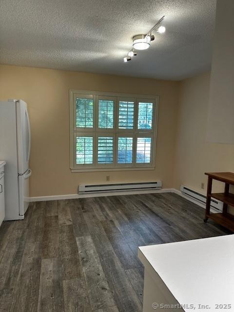 4 Heritage Crst Unit A, Southbury, CT 06488 - unfurnished dining area featuring baseboard heating, wood finished floors, a textured ceiling, and track lighting