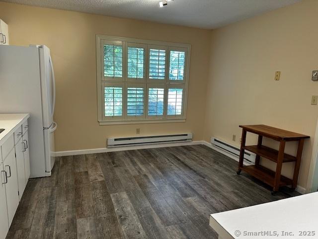 4 Heritage Crst Unit A, Southbury, CT 06488 - unfurnished dining area with a baseboard heating unit and dark wood-style flooring