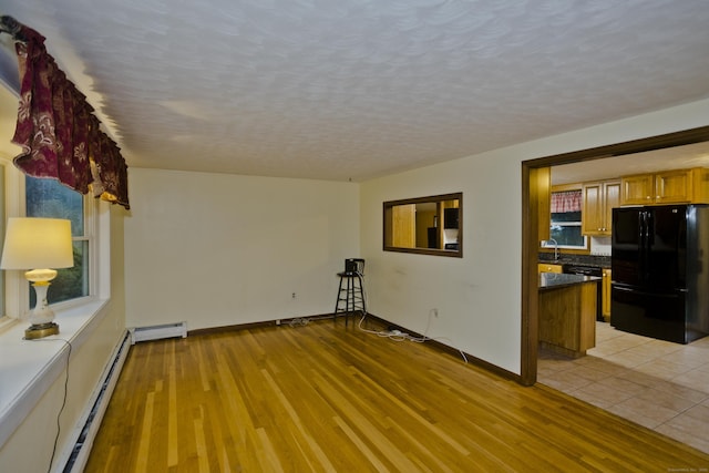 4 Birchwood Ter, Enfield, CT 06082 - unfurnished living room featuring a baseboard heating unit, light wood-style floors, a textured ceiling, and a baseboard radiator