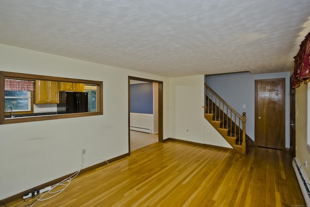 4 Birchwood Ter, Enfield, CT 06082 - unfurnished living room with a baseboard heating unit, a baseboard radiator, light wood finished floors, stairway, and a textured ceiling