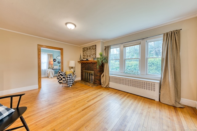 7 Ellsworth St, East Hartford, CT 06108 - living area featuring radiator, light wood-type flooring, ornamental molding, and a brick fireplace