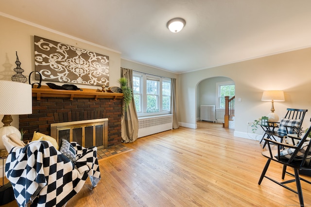 7 Ellsworth St, East Hartford, CT 06108 - living room with radiator heating unit, a brick fireplace, wood finished floors, arched walkways, and ornamental molding