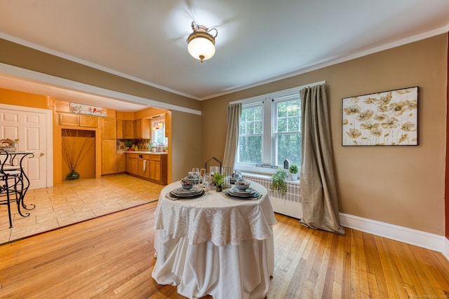 7 Ellsworth St, East Hartford, CT 06108 - dining area featuring radiator heating unit, light wood-style flooring, and ornamental molding