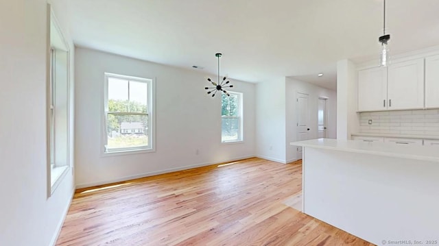 55A Moulthrop St, Ansonia, CT 06401 - kitchen featuring healthy amount of natural light, backsplash, light wood-style flooring, and white cabinetry
