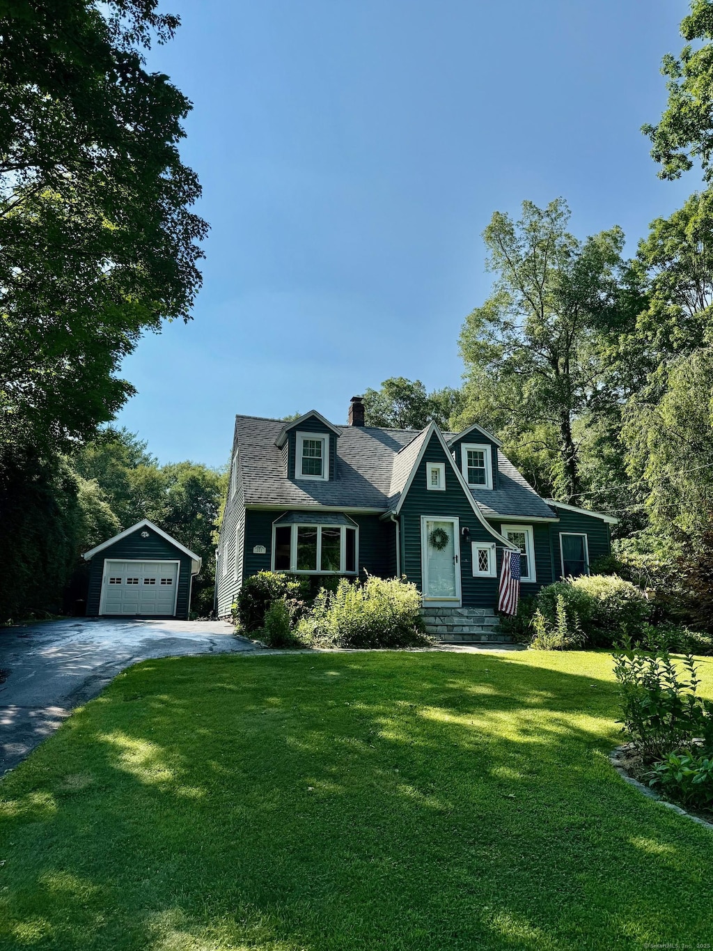 101 Shadduck Rd, Middlebury, CT 06762 - view of front of house with a garage, an outbuilding, asphalt driveway, a chimney, and a front lawn