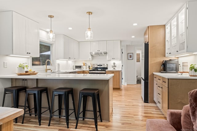 12 Warner Rd, East Haddam, CT 06423 - kitchen with electric stove, a peninsula, light wood-type flooring, a kitchen bar, and under cabinet range hood