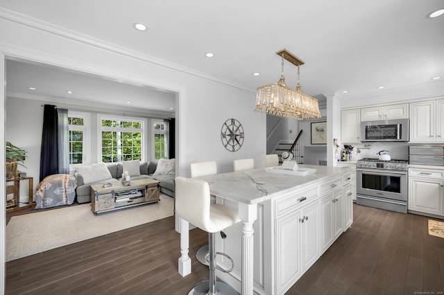 423 Whitfield St, Guilford, CT 06437 - kitchen featuring stainless steel appliances, white cabinets, ornamental molding, dark wood-style flooring, and a breakfast bar area