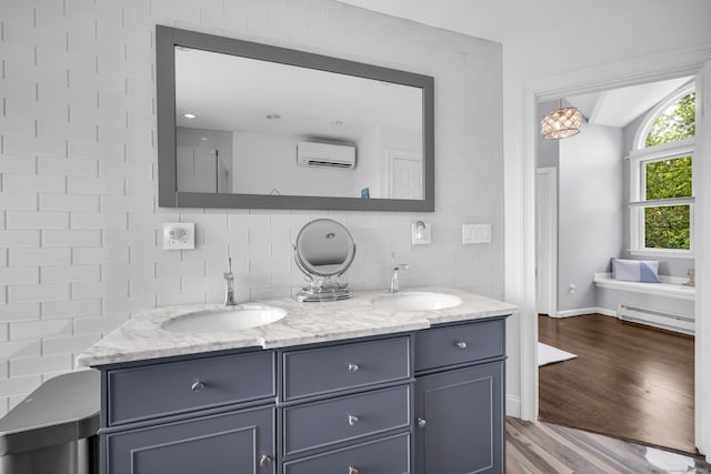 423 Whitfield St, Guilford, CT 06437 - full bathroom with an AC wall unit, double vanity, baseboard heating, wood finished floors, and tasteful backsplash