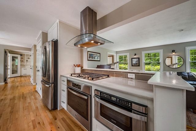 310 Opening Hill Rd, Madison, CT 06443 - kitchen with stainless steel appliances, island exhaust hood, a peninsula, light countertops, and light wood-style floors