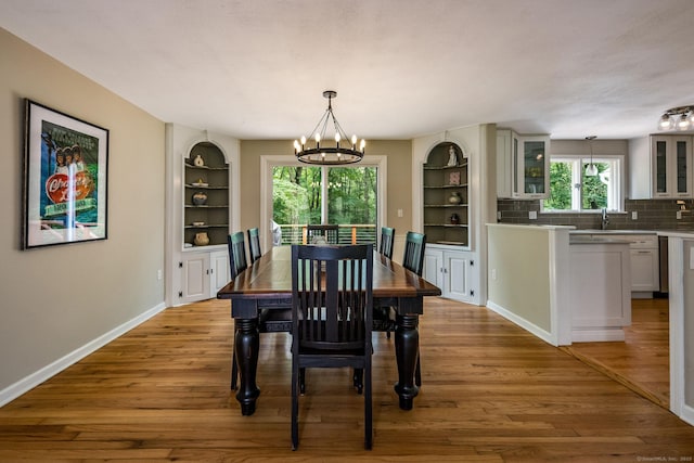 310 Opening Hill Rd, Madison, CT 06443 - dining area featuring a chandelier, built in shelves, wood finished floors, and healthy amount of natural light