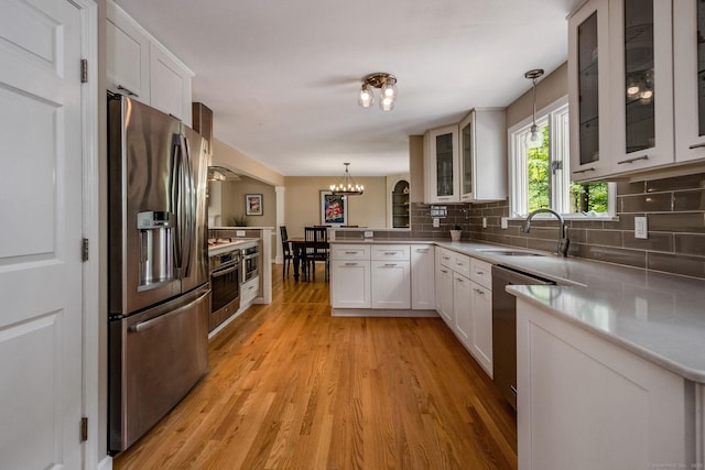 310 Opening Hill Rd, Madison, CT 06443 - kitchen with appliances with stainless steel finishes, a peninsula, a chandelier, light wood-style floors, and backsplash