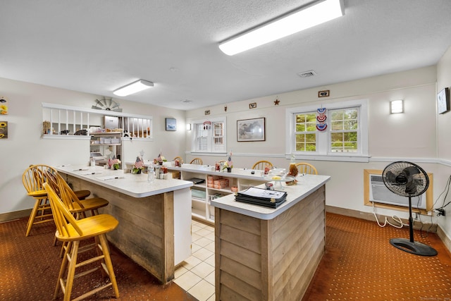 678 Colonel Ledyard Hwy, Ledyard, CT 06339 - kitchen featuring a kitchen breakfast bar, light countertops, a peninsula, a wall mounted air conditioner, and a textured ceiling