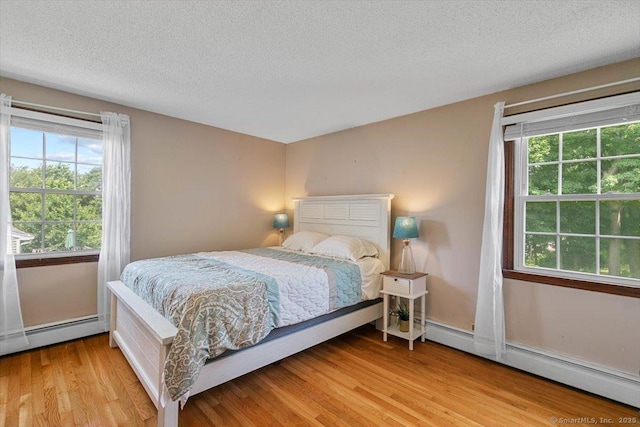 822 New Haven Ave, Milford, CT 06460 - bedroom with baseboard heating, multiple windows, light wood finished floors, and a textured ceiling