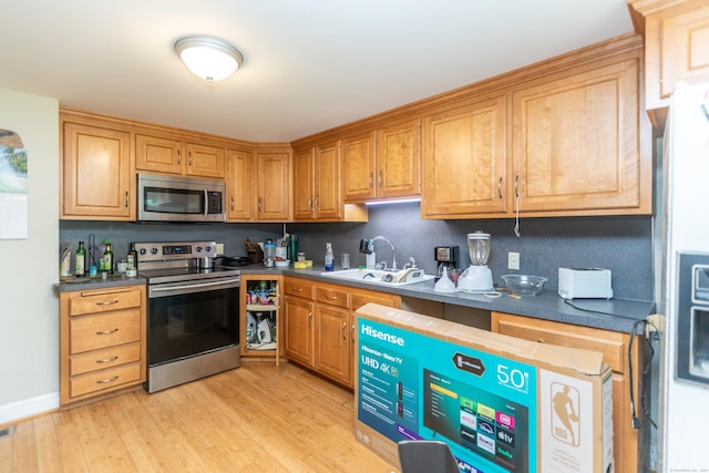 19 Main St, Plymouth, CT 06786 - kitchen featuring appliances with stainless steel finishes, light wood finished floors, dark countertops, and brown cabinets