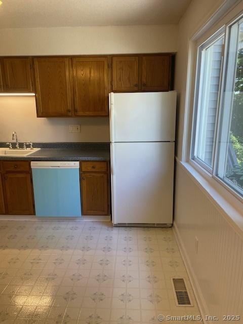 273 Derby Ave Unit 810, Derby, CT 06418 - kitchen with freestanding refrigerator, dishwashing machine, light floors, brown cabinetry, and dark countertops