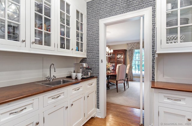 9 Tallwood Rd, Woodbridge, CT 06525 - kitchen with butcher block counters, crown molding, glass insert cabinets, a chandelier, and light wood-style flooring