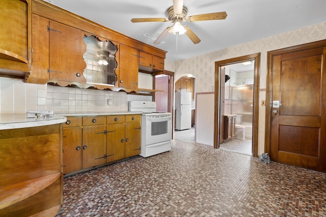 460 Stonybrook Rd, Stratford, CT 06614 - kitchen featuring white appliances, wallpapered walls, wainscoting, brown cabinetry, and arched walkways