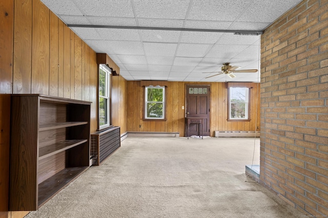 460 Stonybrook Rd, Stratford, CT 06614 - unfurnished living room featuring baseboard heating, a baseboard heating unit, carpet, wooden walls, and a drop ceiling