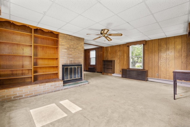 460 Stonybrook Rd, Stratford, CT 06614 - unfurnished living room featuring ceiling fan, carpet flooring, a brick fireplace, wooden walls, and a drop ceiling