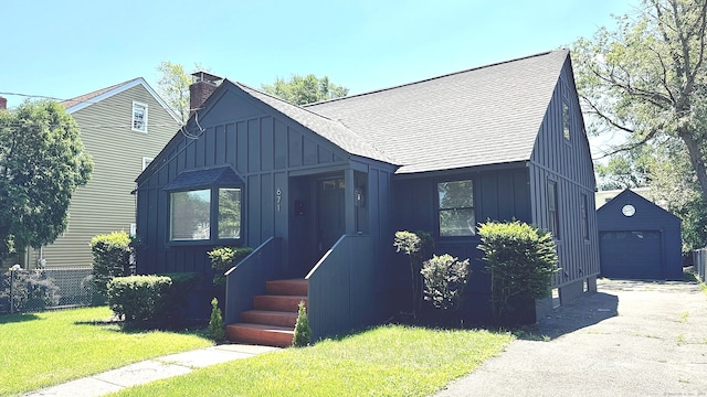 671 Fairview Ave, Bridgeport, CT 06606 - view of front of property with board and batten siding, an outdoor structure, a garage, asphalt driveway, and a shingled roof