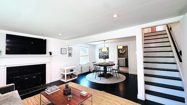 671 Fairview Ave, Bridgeport, CT 06606 - living room with radiator, dark wood-style floors, a fireplace with flush hearth, recessed lighting, and stairs