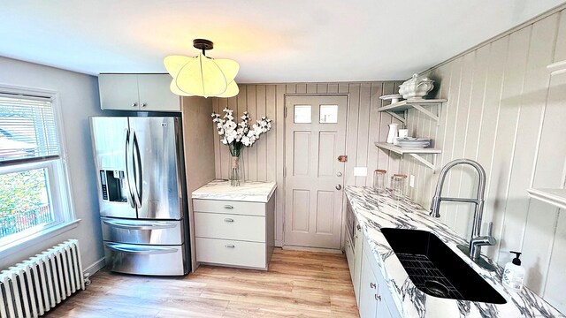 671 Fairview Ave, Bridgeport, CT 06606 - kitchen with stainless steel fridge with ice dispenser, radiator heating unit, open shelves, light wood-style floors, and wood walls