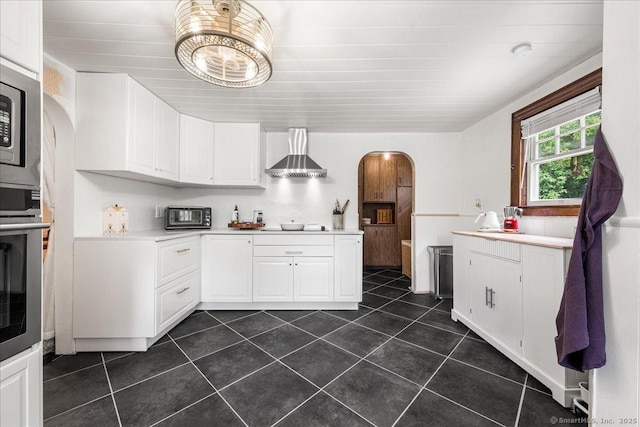 10 Gifford Ln, Norwich, CT 06389 - kitchen with wall chimney range hood, arched walkways, dark tile patterned flooring, white cabinets, and light countertops