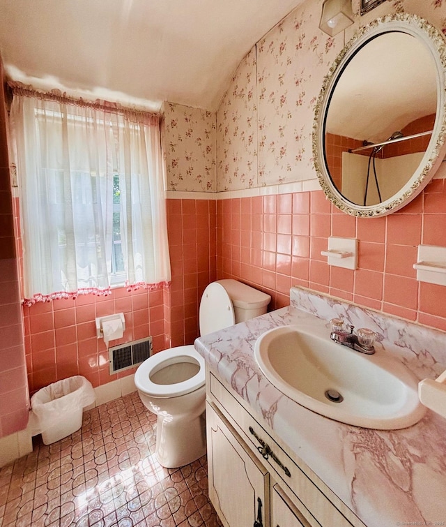 84 Blamey Cir, Stratford, CT 06614 - bathroom featuring tile walls, wallpapered walls, vanity, lofted ceiling, and a wainscoted wall