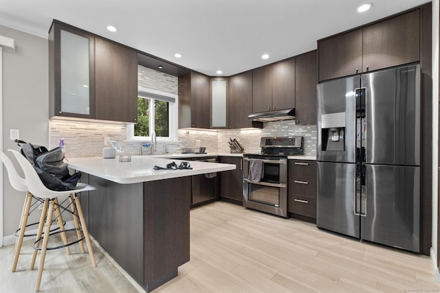 3 Radio Pl Unit 3, Stamford, CT 06906 - kitchen with stainless steel appliances, under cabinet range hood, dark brown cabinets, a peninsula, and light countertops