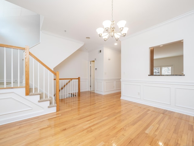 570 Danbury Rd Unit 14, Ridgefield, CT 06877 - unfurnished living room featuring ornamental molding, wood finished floors, a chandelier, wainscoting, and a decorative wall