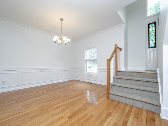 570 Danbury Rd Unit 14, Ridgefield, CT 06877 - unfurnished dining area featuring crown molding, a chandelier, stairway, light wood-style floors, and a wainscoted wall