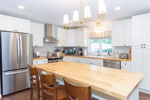 34 Taft St, Killingly, CT 06239 - kitchen featuring butcher block countertops, stainless steel appliances, wall chimney exhaust hood, white cabinets, and tasteful backsplash