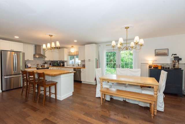 34 Taft St, Killingly, CT 06239 - kitchen featuring appliances with stainless steel finishes, a chandelier, butcher block counters, wall chimney exhaust hood, and white cabinetry