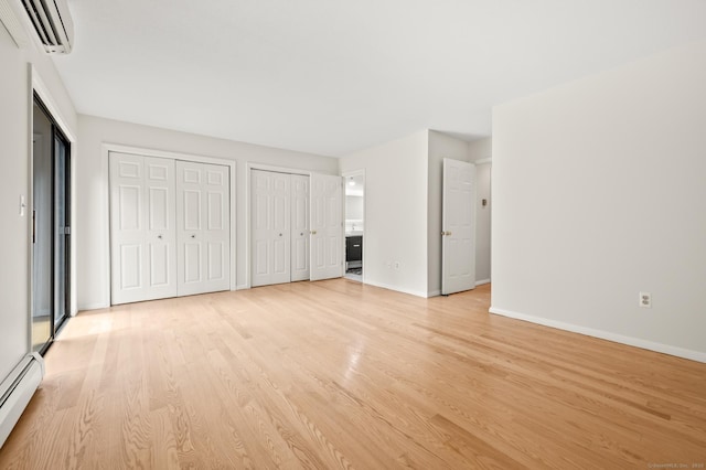 11 Danforth Ln Unit 11, Rocky Hill, CT 06067 - unfurnished bedroom with a wall mounted AC, a baseboard radiator, light wood finished floors, and multiple closets
