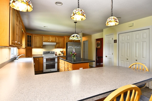 32 Sable Dr, Ledyard, CT 06339 - kitchen with double oven range, freestanding refrigerator, under cabinet range hood, a center island, and brown cabinetry