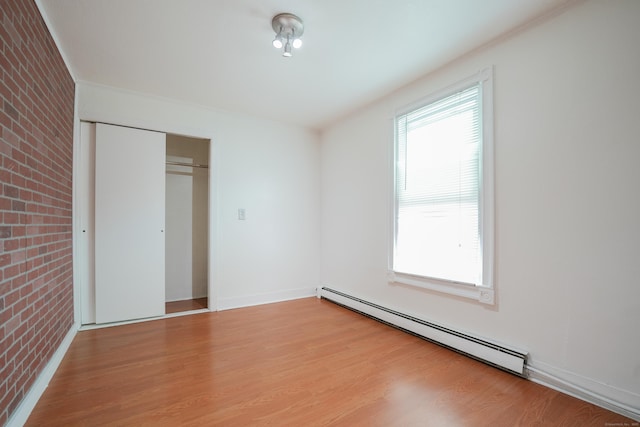 72 Harral Ave, Bridgeport, CT 06604 - unfurnished bedroom with a baseboard heating unit, brick wall, light wood finished floors, and a closet