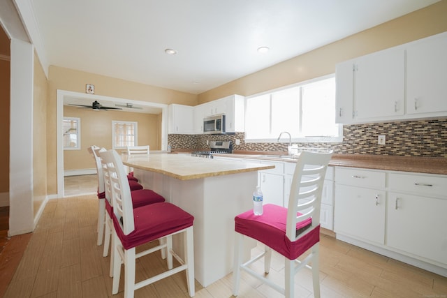 72 Harral Ave, Bridgeport, CT 06604 - kitchen featuring appliances with stainless steel finishes, backsplash, a kitchen bar, white cabinetry, and recessed lighting