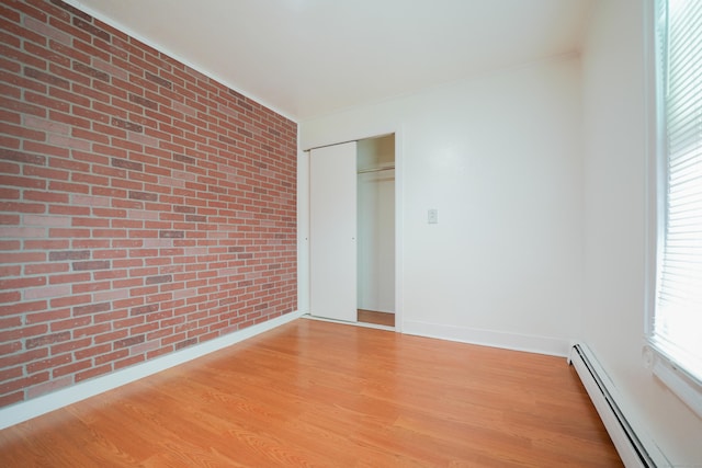 72 Harral Ave, Bridgeport, CT 06604 - unfurnished bedroom with a baseboard heating unit, brick wall, light wood-style flooring, a closet, and crown molding