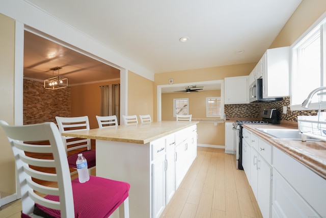 72 Harral Ave, Bridgeport, CT 06604 - kitchen with appliances with stainless steel finishes, white cabinetry, backsplash, a center island, and a kitchen breakfast bar