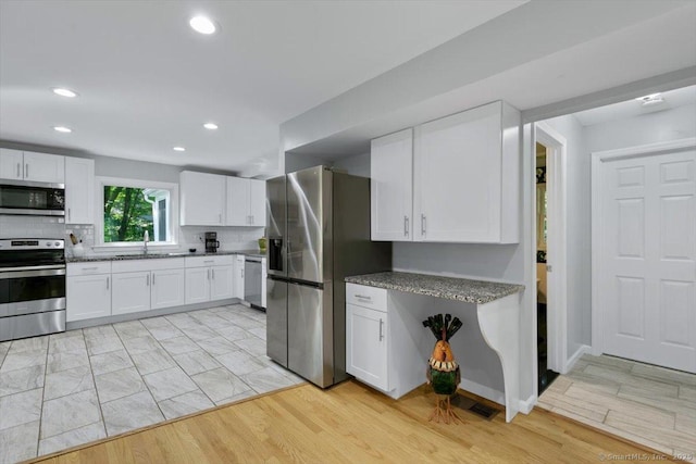 330 Foxwood Rd, Guilford, CT 06437 - kitchen featuring appliances with stainless steel finishes, white cabinets, recessed lighting, decorative backsplash, and dark stone counters