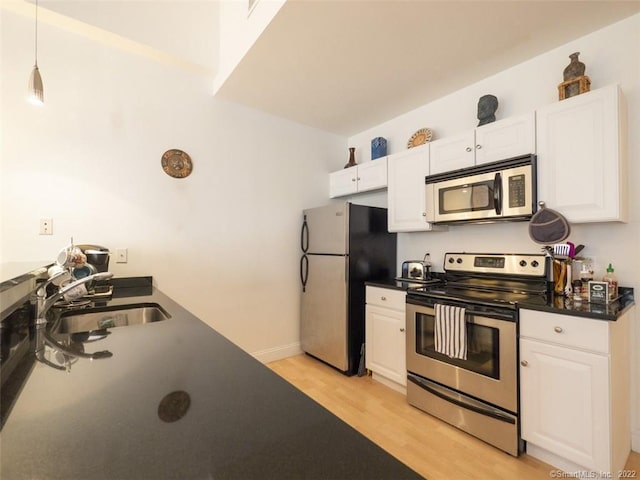 124 Court St Unit 8, New Haven, CT 06511 - kitchen with stainless steel appliances, light wood-style flooring, dark countertops, white cabinetry, and pendant lighting