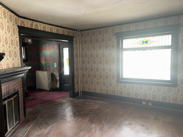 607 Broadview Ter, Hartford, CT 06106 - unfurnished living room with radiator heating unit, dark wood-type flooring, wallpapered walls, and a brick fireplace