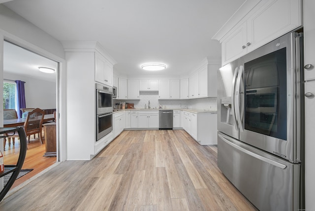 35 Flax Mill Ter, Milford, CT 06461 - kitchen with stainless steel appliances, light countertops, light wood-type flooring, white cabinetry, and decorative backsplash