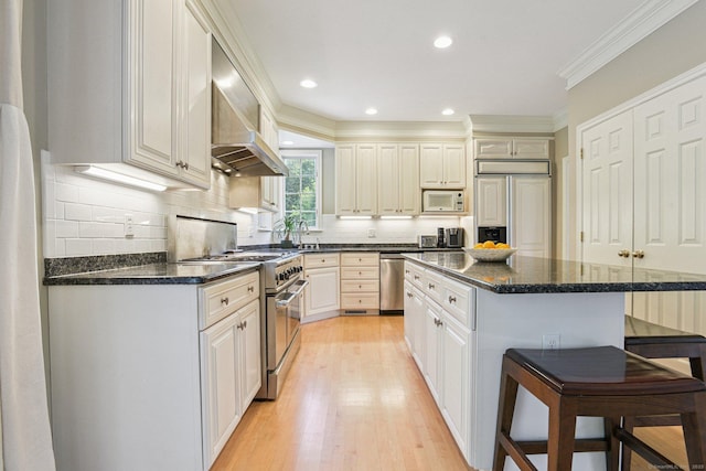 61 Brookview Ct, Groton, CT 06340 - kitchen featuring premium appliances, a kitchen bar, light wood-type flooring, wall chimney exhaust hood, and a kitchen island