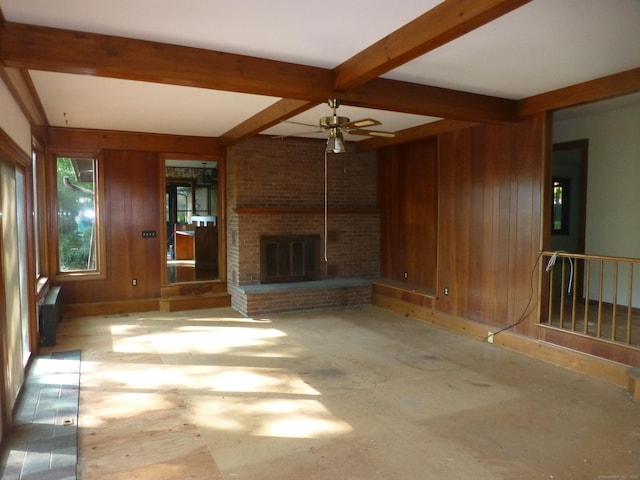 5 Tower Hill Lake Rd, Deep River, CT 06417 - unfurnished living room with wood walls, beamed ceiling, a fireplace, and a ceiling fan
