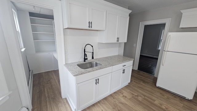 62 Miller St, New Britain, CT 06053 - kitchen with freestanding refrigerator, light wood-type flooring, baseboard heating, white cabinets, and decorative backsplash