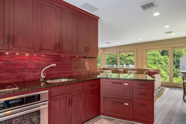 8 Up The Rd, Simsbury, CT 06092 - kitchen with stainless steel oven, light wood-style floors, decorative backsplash, dark stone countertops, and recessed lighting