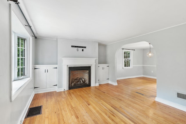 3 Lynette Dr, North Haven, CT 06473 - unfurnished living room with light wood-style flooring, a fireplace, arched walkways, and crown molding