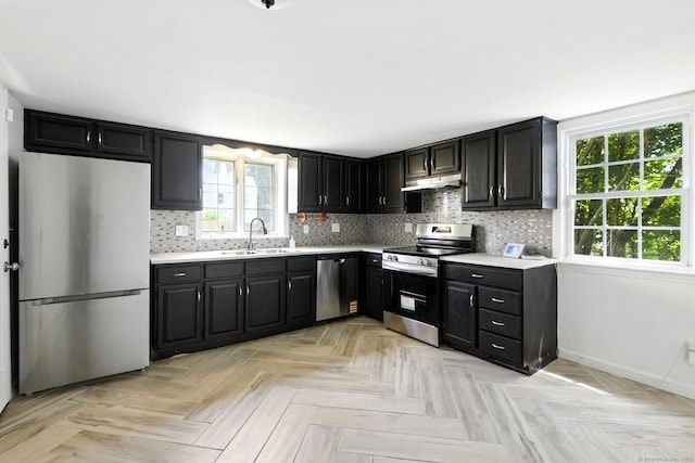 5 Church St Apt R, East Windsor, CT 06016 - kitchen featuring appliances with stainless steel finishes, light countertops, decorative backsplash, under cabinet range hood, and dark cabinets