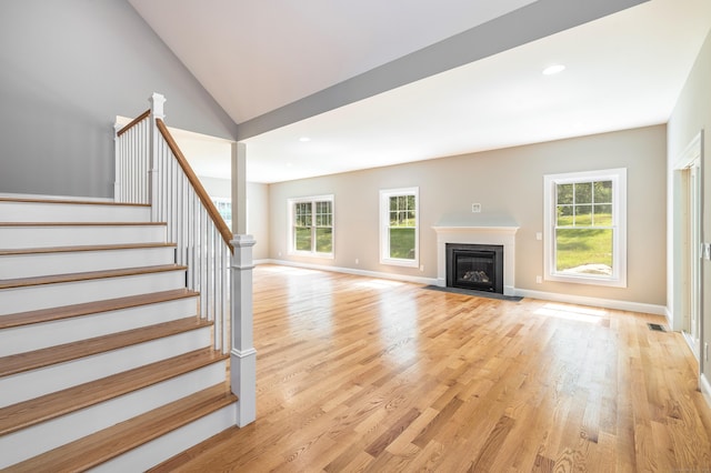 6 Kaatskill Ln, East Lyme, CT 06357 - unfurnished living room with healthy amount of natural light, light wood-style flooring, stairway, a fireplace with flush hearth, and lofted ceiling